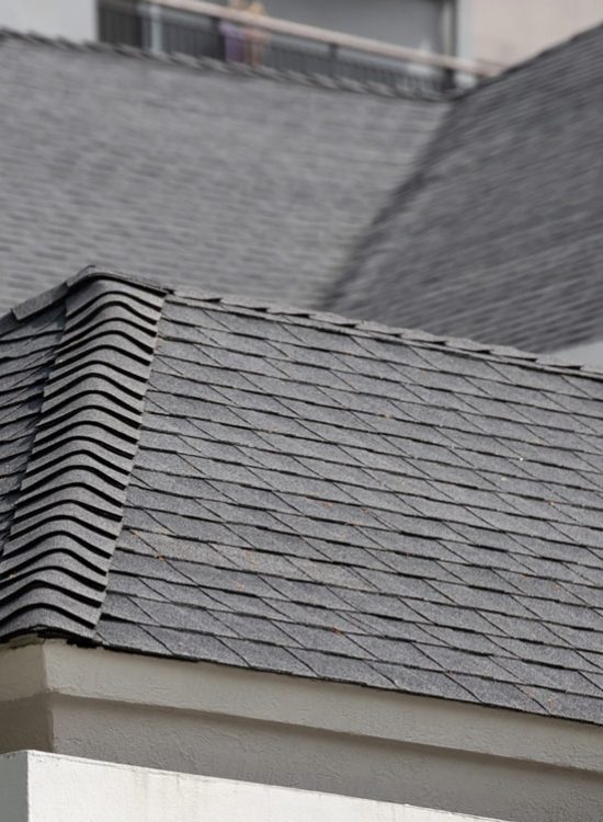 A close-up of a roof covered in asphalt shingle emphasizing the ridges