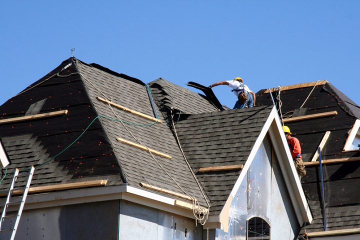 A team of roofers wearing hard hat doing a roof repair job on a house